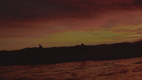 Pan-follows-jet-ski-patrol-leading-silhouette-of-surfer-launching-into-huge-air-off-lip-of-wave