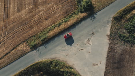 An-aerial-view-of-a-red-vintage-convertible-car-driving-through-agricultural-fields-in-Germany