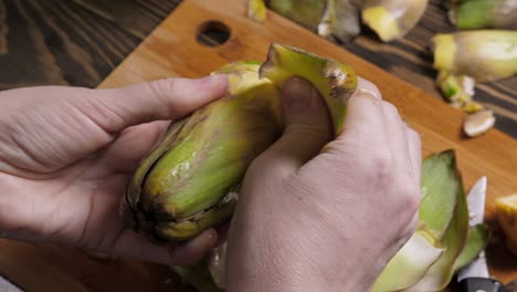 Woman-cleaning-artichokes.-Cooking-process-at-the-kitchen.-Closeup