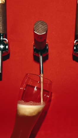 Bartender-slowly-pouring-delicious-lager-foamy-beer-in-glass-against-red-background.-Bubbles.-Beer-bar,-relaxation.-Drink,-brewery,-bar,-degustation,-festival,-drink-texture-concept.-Vertical-layout