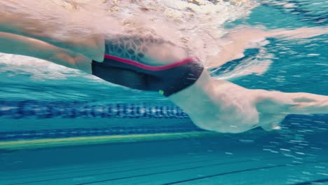 Swimming-techniques.-Athletic-young-man-in-motion,-training,-swimming-in-pool,-wearing-cap-and-goggles.-Concept-of-pool-sports,-water-sport,-competition,-active-lifestyle