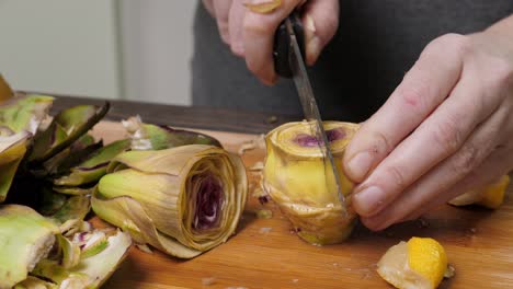 Woman-cleaning-artichokes-with-knife.-Cooking-process-at-the-kitchen.-Closeup