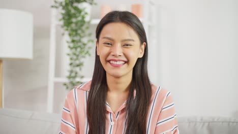 Portrait-of-Asian-beautiful-woman-sit-on-sofa-in-living-room-at-home.-Attractive-young-female-feeling-happy-and-relax-enjoy-early-morning-weekend-activity-lifestyle-in-house-and-smile,-look-at-camera.