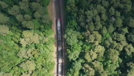 Train-goes-along-Railway-through-summer-forest.-Aerial-view-from-drone