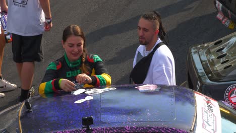 Female-pilot-handing-gifts-and-talking-to-fans-during-the-car-exhibition-closer-shot