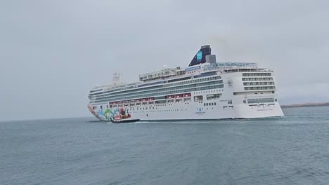 Das-Video-Zeigt-Das-Kreuzfahrtschiff-MSC-Norwegian-Pearl,-Das-Den-Hafen-Von-Reykjavik-Verlässt,-Während-Ein-Kleinerer-Schlepper-Für-Einen-Notfall-Patrouilliert.