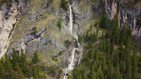 Imágenes-Aéreas-De-Una-Cascada-Vertical-Que-Cae-Por-Escarpados-Acantilados-Rocosos-En-Las-Dolomitas,-Rodeada-De-Un-Bosque-Verde.