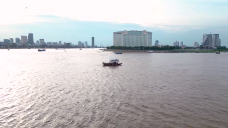 Drone-shot-of-ferry-service-transportation-on-Mekong-River-with-Sokha-Hotel-in-view