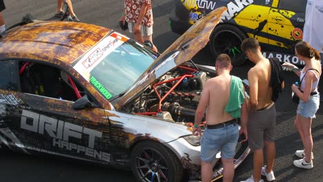 People-checking-on-a-race-car-under-the-hood-during-the-car-exhibition