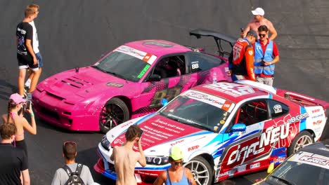 People-checking-on-race-cars-during-the-car-exhibition-and-talking-with-the-pilots