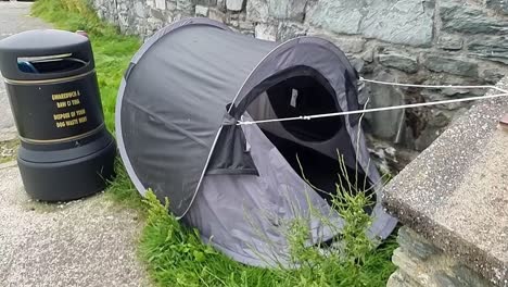 Abandoned-homeless-persons-camping-tent-alongside-council-trash-bin-in-Welsh-seaside-town