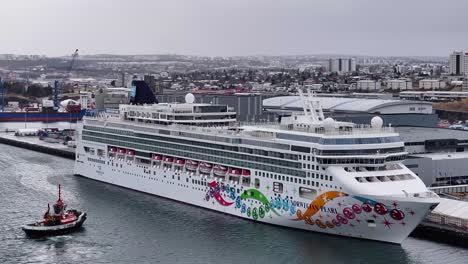 Das-Kreuzfahrtschiff-MSC-Norwegian-Pearl-Ist-Im-Hafen-Von-Reykjavik-Mit-Einem-Farbenfrohen-Design-Und-Einem-Roten-Schlepper-Zu-Sehen,-Der-Seine-Abfahrt-Unterstützt