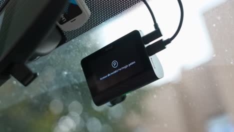 Dash-cam-attached-to-windshield,-screen-display-shows-video-recording-and-parking-mode