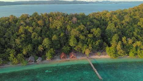 Aerial-tilt-down-view-captures-a-pristine-tropical-coastline-with-a-long-pier-extending-into-the-turquoise-waters-in-Kri-Island,-Raja-Ampat-in-Indonesia