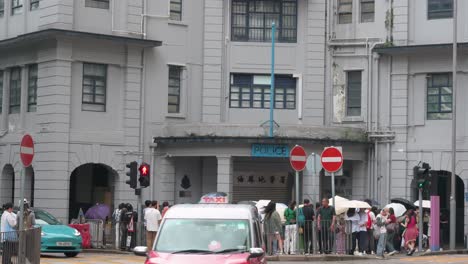 In-the-rain,-groups-of-Chinese-tourists-assemble-outside-the-former-Yau-Ma-Tei-Police-Station,-a-renowned-site-featured-in-many-Hong-Kong-films-and-TV-shows