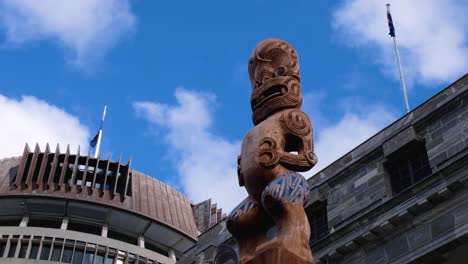 Close-up-of-Maori-Te-Kāhui-Mōuri-taonga-carved-statue-outside-the-Beehive-Parliament-building-landmark-in-capital-city-of-Wellington-NZ-Aotearoa