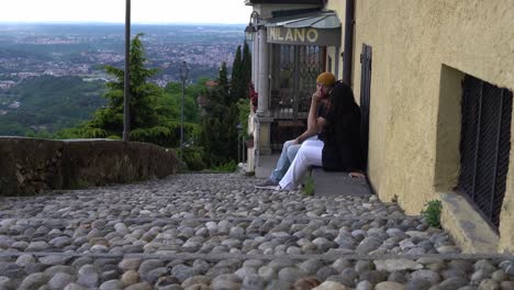 Lovers-sitting-in-small-town-of-Italy-and-enjoying-views,-static-view