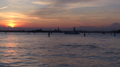 Bezaubernder-Sonnenuntergang-über-Der-Lagune-Von-Venedig,-Mit-Den-Silhouetten-Von-Booten-Und-Historischen-Gebäuden,-Die-Eine-Ruhige-Und-Malerische-Szene-Schaffen