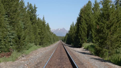 Rocky-mountains-peak,-empty-railroad-train-track,-Banff-National-park-forest