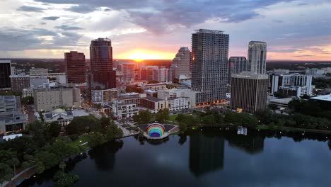 Sunset-over-Downtown-Orlando-skyline-with-high-rise-buildings-and-the-rainbow-amphitheater-at-Lake-Eola