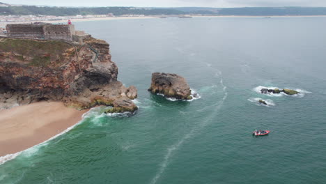 Fantastische-Luftaufnahme-Im-Orbit-über-Dem-Berühmten-Leuchtturm-Von-Nazare-In-Portugal-An-Einem-Sommertag