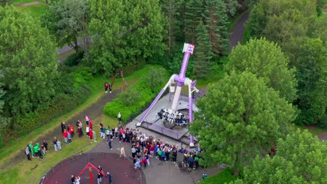 Toma-Aérea-De-Un-Dron-De-Atracciones-En-Un-Parque-Temático-Con-Gente-Disfrutando-De-Los-Juegos-Y-La-Naturaleza.