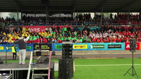 Audience-cheering-up-in-live-musical-concert-before-football-match-at-Laugardalsholl-Sports-Center-and-stadium,-Rey-Cup-International