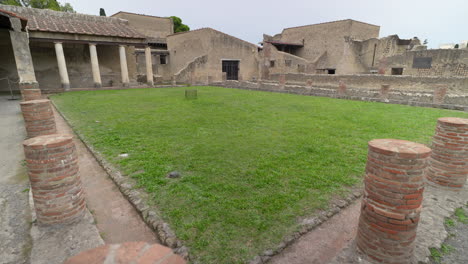 Überreste-Römischer-Villensäulen-Und-Steinmauern,-Die-Einen-Grasbewachsenen-Innenhof-An-Der-Antiken-Stätte-Von-Herculaneum-In-Italien-Umgeben