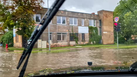 Driving-over-flooded-street-in-Jelgava-Latvia,-affected-infrastructure-massive-flood