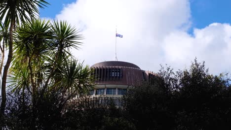 Scenic-view-of-the-iconic-Beehive-New-Zealand-parliament-building-landmark-through-native-cabbage-trees-in-capital-city-of-Wellington-NZ-Aotearoa