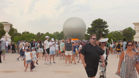 Tourists-gather-around-the-Olympic-cauldron-in-the-Tuileries-Gardens-in-Paris,-France