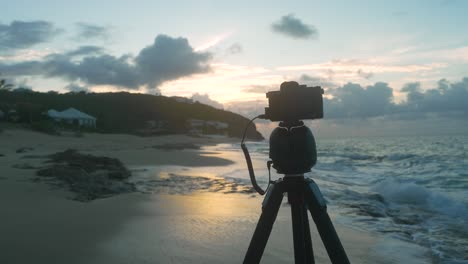 Shot-of-timelapse-camera-capturing-sunset-with-waves-leaving-foam-on-beach