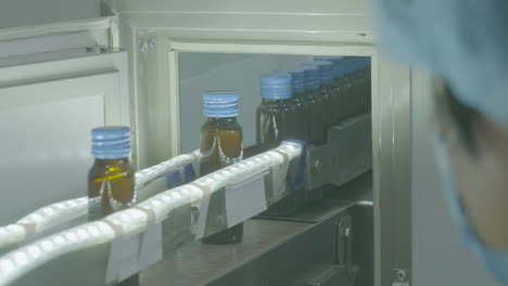 Real-shot-of-pharmaceutical-and-drug-bottling-factory-production-line-featuring-rows-of-medical-glass-bottles-being-manufactured-by-automated-machinery-and-conveyor-belts