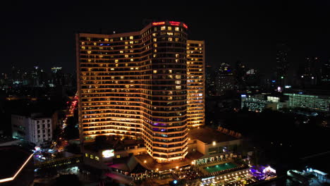 Aerial-view-toward-the-illuminated-Royal-Orchid-Sheraton-Hotel,-night-in-Bangkok