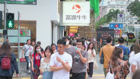 Pedestrians-walk-past-a-commercial-logo-sign-from-the-Chinese-digitized-brokerage-and-wealth-management-platform,-Futu-Holdings,-in-Hong-Kong