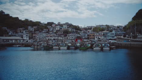 Tranquil-landscape-of-docked-boats-and-traditional-fishing-village-buildings-in-Saikazaki,-Japan,-under-a-cloudy-sky