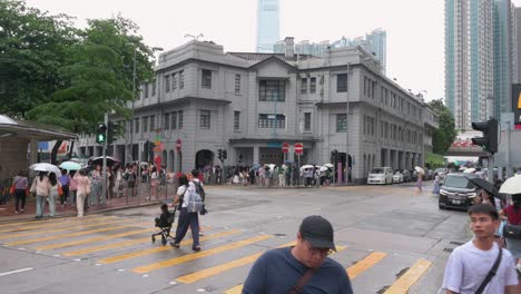 Amidst-the-rain,-Chinese-tourists-congregate-in-front-of-the-former-Yau-Ma-Tei-Police-Station,-a-well-known-landmark-featured-in-numerous-Hong-Kong-films-and-TV-shows