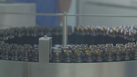 Real-shot-of-pharmaceutical-and-drug-bottling-factory-production-line-featuring-rows-of-medical-glass-bottles-being-manufactured-by-automated-machinery-and-conveyor-belts