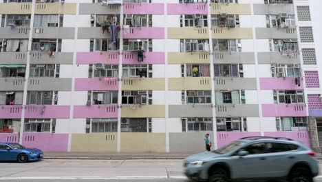 People-walk-the-street-in-front-of-a-colorful-high-rise-public-housing-apartment-building-in-Hong-Kong