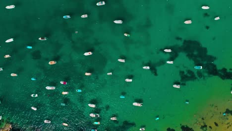 Luftaufnahme-Von-Oben-Auf-Boote,-Die-In-Atemberaubendem-Türkisfarbenem-Wasser-Vor-Anker-Liegen-Und-Eine-Ruhige-Und-Friedliche-Küstenszene-Bieten