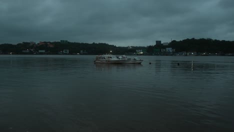 A-boat-floats-on-a-calm-river-under-a-cloudy-evening-sky