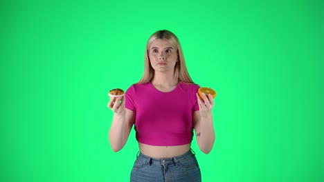 Mujer-Rubia-Joven-Codiciosa-Sosteniendo-Y-Oliendo-Un-Panecillo-Y-Una-Rodaja-De-Naranja,-Comida-Saludable-Y-No-Saludable,-Fotografía-De-Estudio-Con-Fondo-Verde