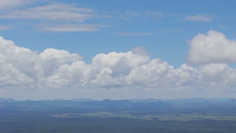 Luftaufnahme-Wunderschöner-Wolken-Am-Blauen-Himmel,-Die-Sich-Langsam-Bewegen,-Mit-Einem-Horizont-Aus-Bergen-In-Der-Ferne