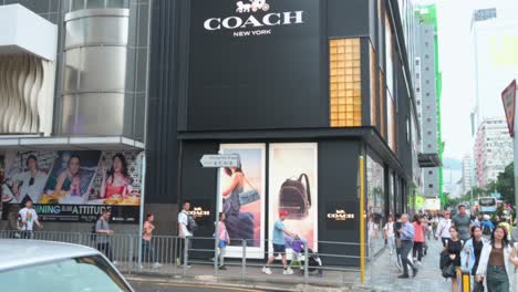 People-walk-past-the-American-multinational-fashion-and-luxury-accessories-chain-brand,-Coach,-store-in-Hong-Kong