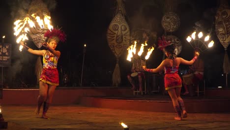 Aufregende-Feuertanzvorführung-Mit-Tänzerinnen-Und-Dramatischen-Flammen-Bei-Einem-Nachtfest-Mit-Trommlern,-Die-Den-Rhythmus-Vorgeben