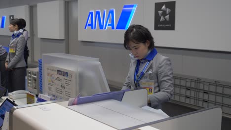 Personal-De-Ana-Trabajando-Diligentemente-En-El-Mostrador-De-Facturación-En-El-Aeropuerto-De-Kansai,-Osaka