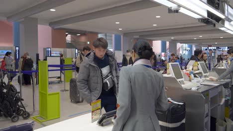 Ein-Detaillierter-Blick-Auf-Die-Interaktion-Zwischen-Einem-Passagier-Und-ANA-Mitarbeitern-Beim-Gepäckcheck-in-Am-Kansai-Flughafen,-Osaka