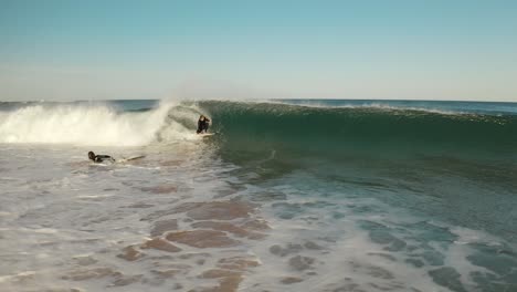 Surfer-getting-barrelled-on-ocean-wave-aerial-view-surfing-at-sunset