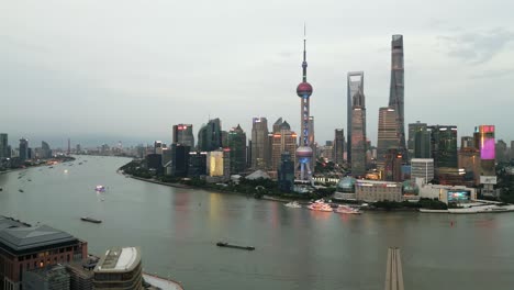 Drone-Panorámico-Del-Paisaje-Urbano-De-Lujiazui,-Shanghai,-China,-Arquitectura-Simbólica,-Ciudad-Aérea-Después-De-Navegar-En-Calma,-Agua,-Horizonte-Al-Atardecer