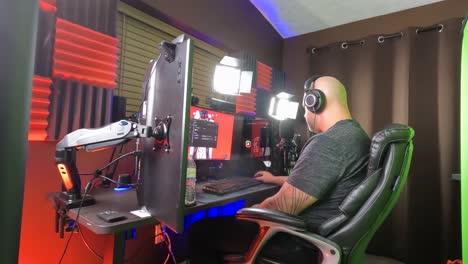 Focused-streamer-working-in-a-soundproof-studio,-engaging-with-audience-through-multiple-screens-and-professional-audio-equipment